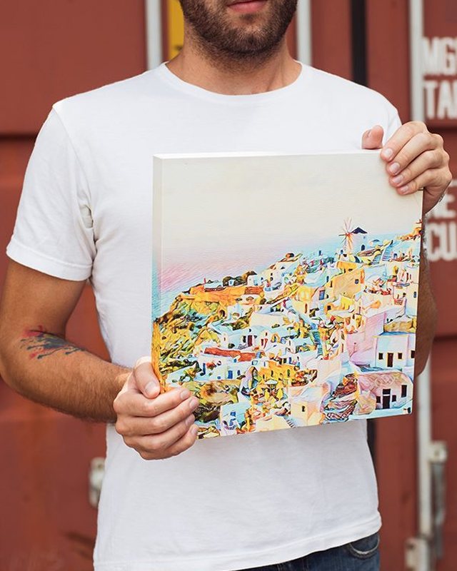 A man holding a colourful canvas print of a hillside town