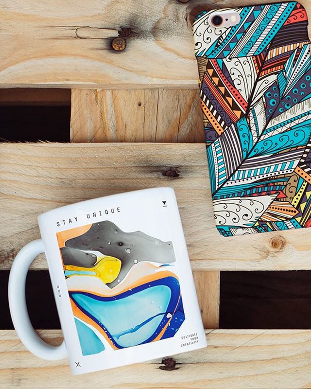 A mug and a patterned phone case on a wooden pallet