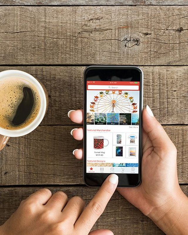Hands holding a phone with the Pixapp shop open, next to a cup of coffee